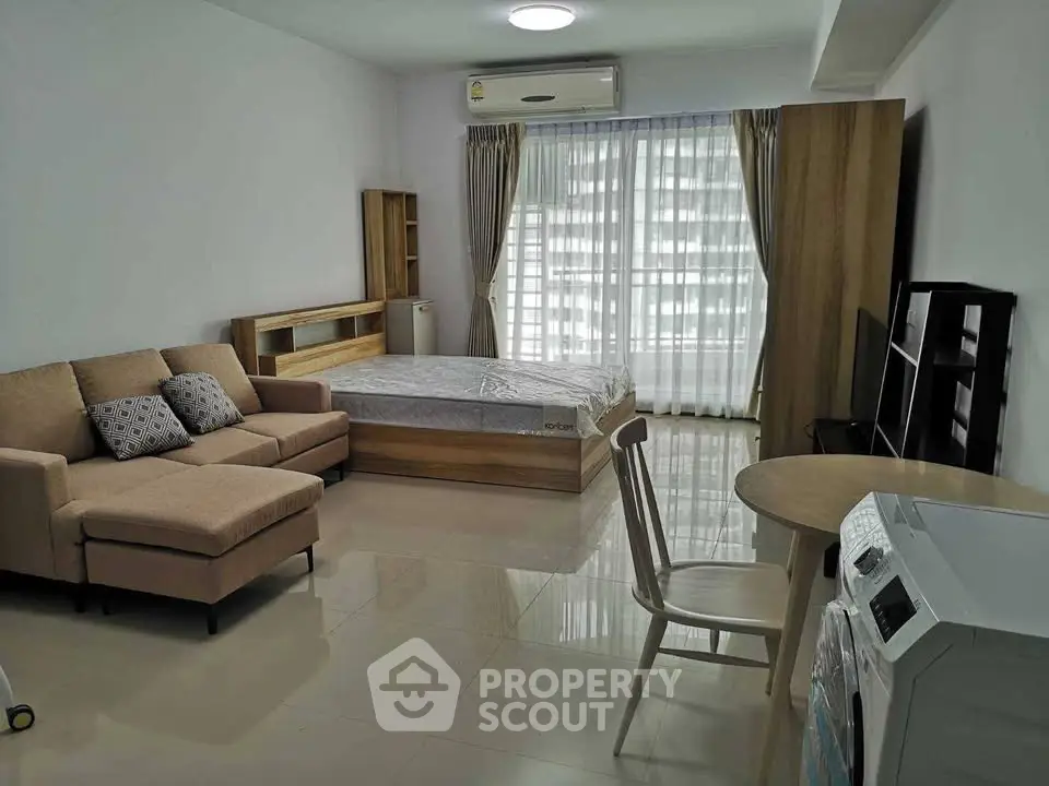Modern studio apartment with cozy living area and washing machine