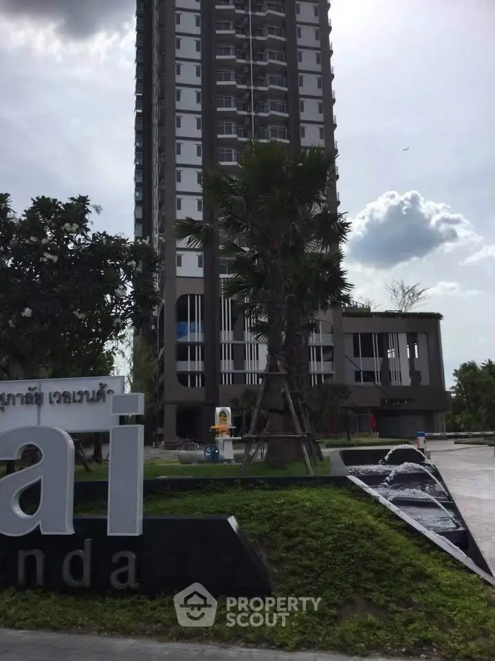 Modern high-rise building with lush landscaping and elegant entrance.
