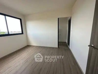 Spacious empty bedroom with large window and wooden flooring