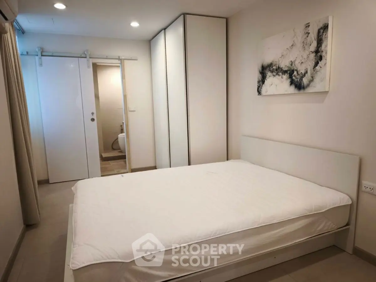 Modern minimalist bedroom with sliding door and abstract art