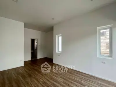 Spacious empty room with wooden flooring and white walls, ready for customization.
