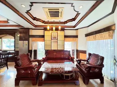 Luxurious living room with elegant wooden furniture and intricate ceiling design.