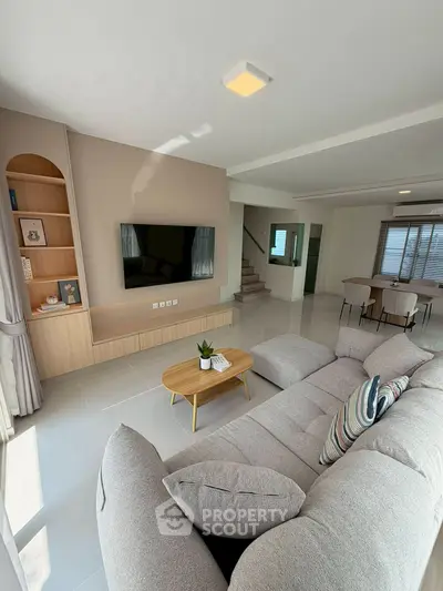 Spacious modern living room with cozy seating and large TV, perfect for relaxation.