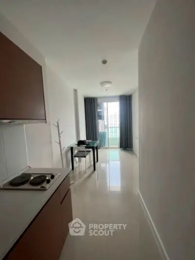 Modern apartment interior with sleek kitchen and city view balcony.