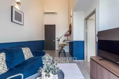 Modern living room with stylish decor and blue accents, featuring a cozy sofa and wall-mounted TV.