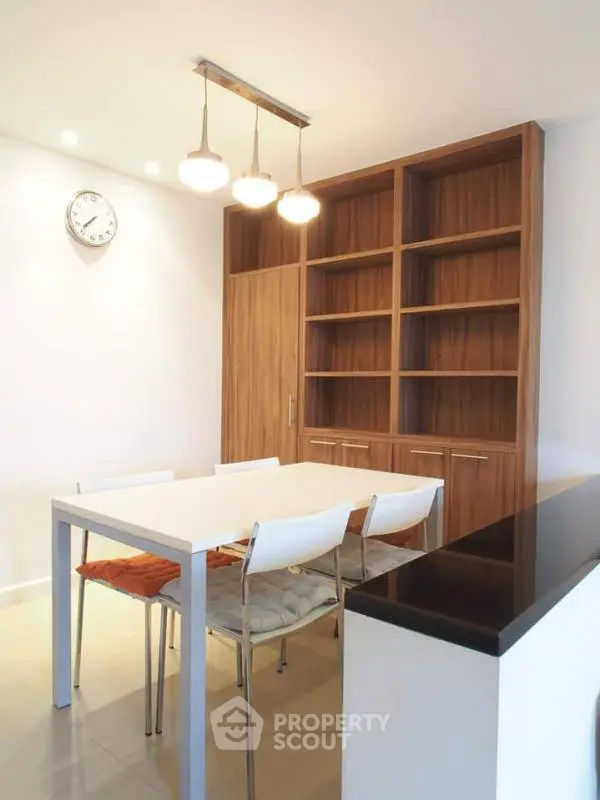 Modern dining area with sleek table, chairs, and built-in wooden shelves.
