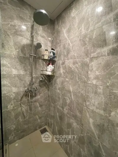 Luxurious marble-tiled shower with modern fixtures and built-in shelf.