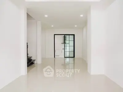 Spacious modern interior with sleek tile flooring and glass door, ideal for versatile living space.