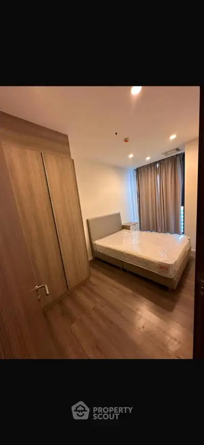 Modern bedroom with wooden flooring and large wardrobe in a stylish apartment.