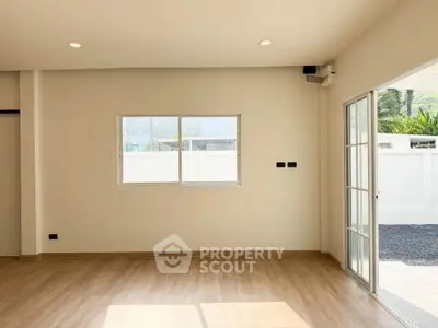 Bright and spacious living room with wooden flooring and large windows in modern home.
