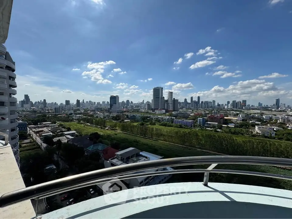 Stunning cityscape view from a high-rise balcony with clear blue skies.