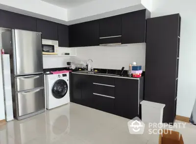 Modern kitchen with sleek black cabinets, stainless steel appliances, and washing machine.