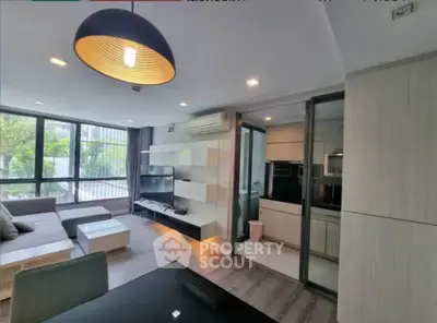 Modern living room with open kitchen, stylish decor, and large windows for natural light.