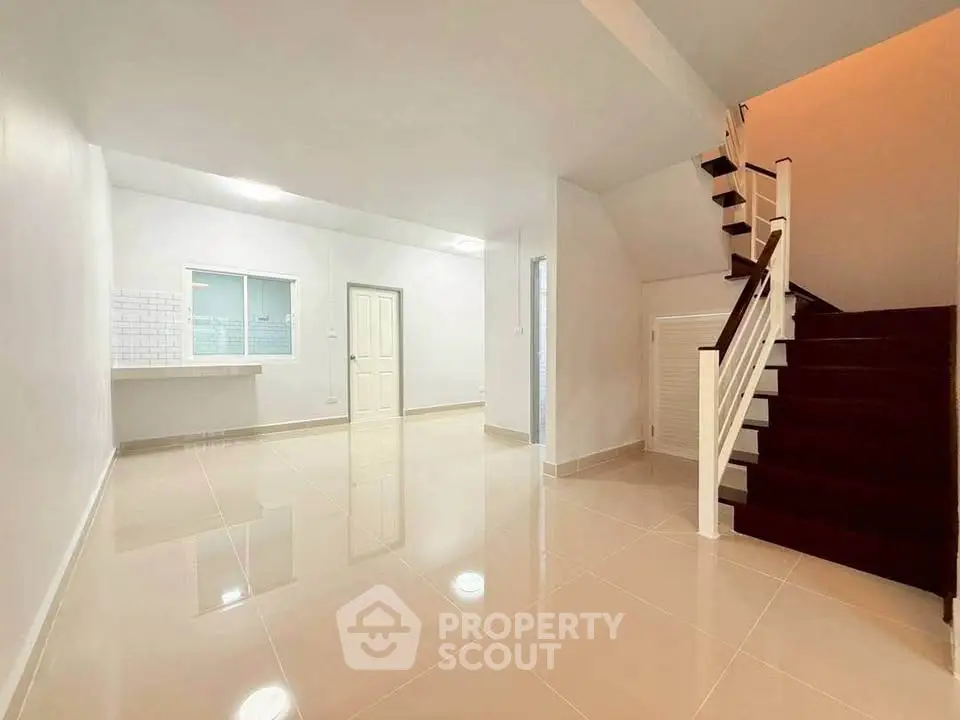 Spacious open-plan living area with modern staircase and glossy tiled floors