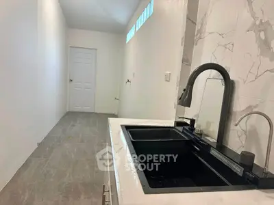 Modern kitchen with sleek black sink and marble backsplash in a minimalist design.