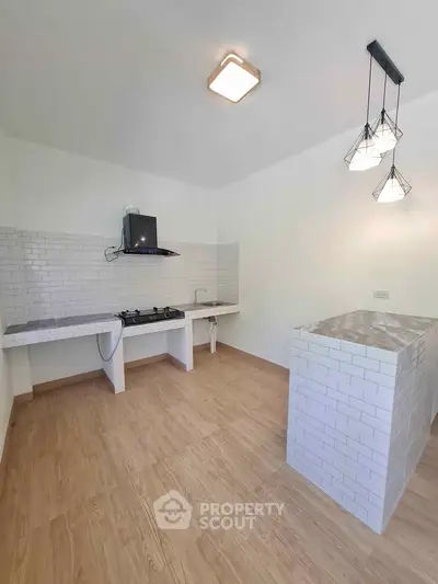 Modern kitchen with open layout and gas stove, featuring stylish pendant lighting.