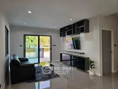 Modern living room with sleek furniture and large glass doors opening to a serene garden view.