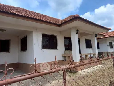 Charming single-story home with red-tiled roof and fenced yard under blue skies.