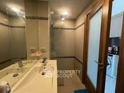 Modern bathroom with sleek fixtures and glass shower in a contemporary apartment.