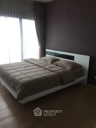 Modern bedroom with large window and elegant curtains, featuring a stylish bed and hardwood floors.