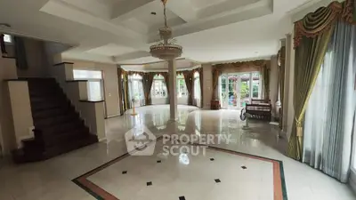 Spacious elegant living room with chandelier and large windows in luxury home.