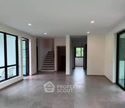 Spacious modern living room with large windows and staircase in a contemporary home.