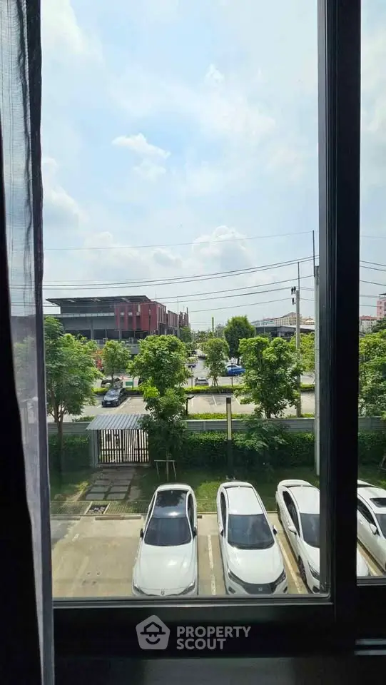 Scenic view from a window overlooking parked cars and lush greenery.