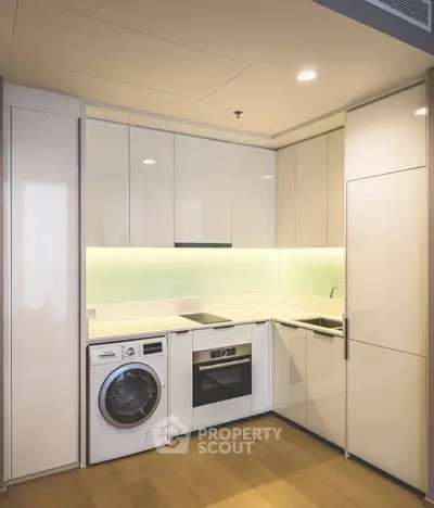 Modern kitchen with sleek cabinetry, built-in appliances, and washing machine in compact layout.
