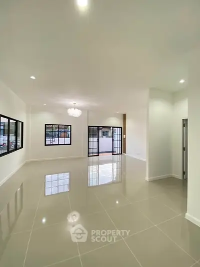 Spacious modern living room with glossy tiled floors and elegant chandelier.