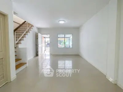 Spacious unfurnished living room with staircase and large window
