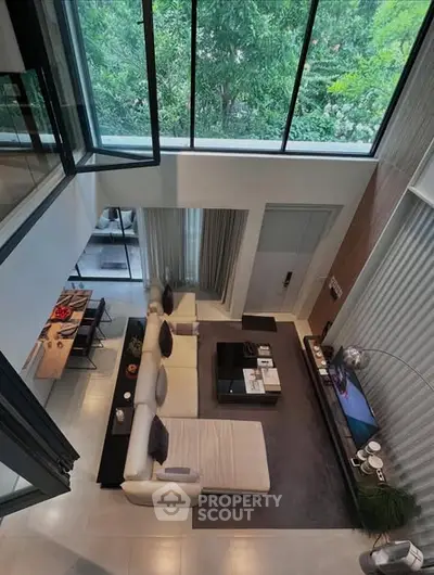 Stunning modern living room with high ceilings and large windows overlooking greenery.