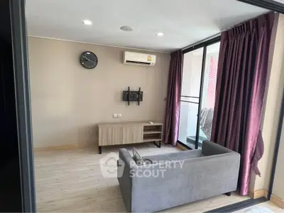 Modern living room with sleek design and balcony access, featuring a cozy sofa and wall-mounted air conditioning.