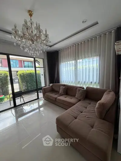 Elegant living room with chandelier and large windows overlooking garden