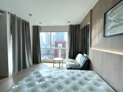 Modern bedroom with city view, featuring large windows and stylish decor.