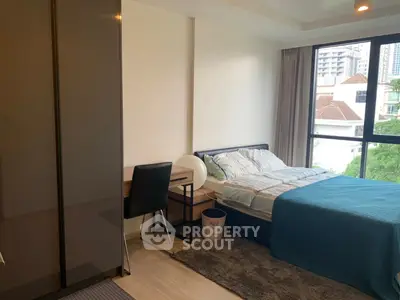 Modern bedroom with city view, featuring sleek furniture and natural light.