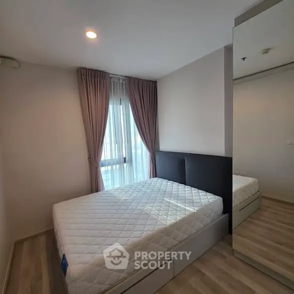 Modern bedroom with large window and stylish curtains in a contemporary apartment.