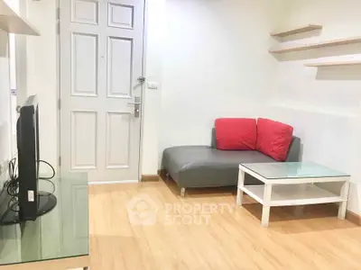Cozy living room with modern decor and wooden flooring, featuring a stylish sofa and glass coffee table.