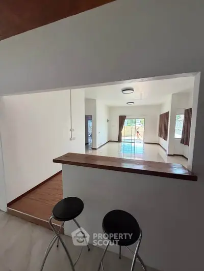 Spacious open-plan living area with bar counter and large windows for natural light.