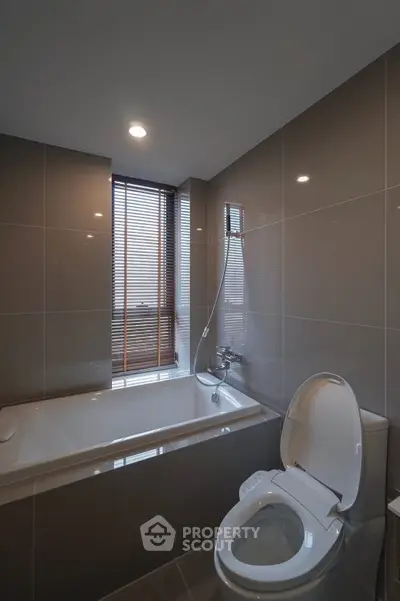 Modern bathroom with sleek design featuring a bathtub and toilet, perfect for relaxation.