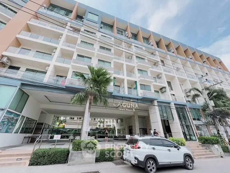 Modern multi-story building with balconies and palm trees, ideal for urban living.