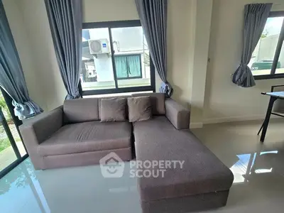 Modern living room with stylish gray sectional sofa and large windows with blue curtains.