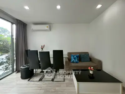 Modern living room with sleek dining set and cozy sofa, featuring large windows for natural light.