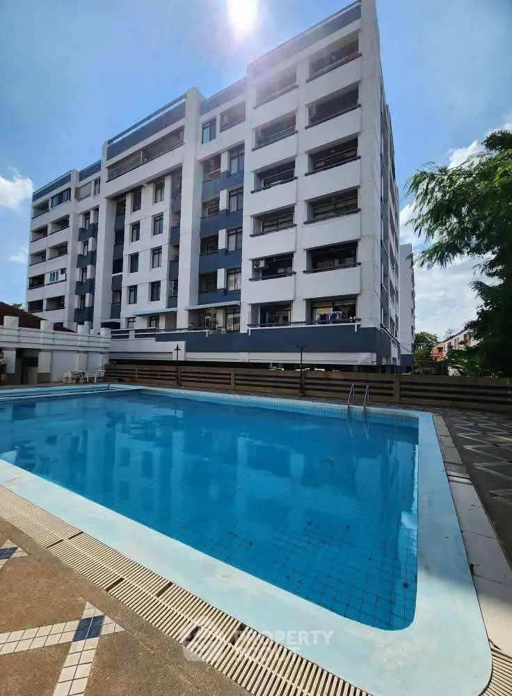 Modern apartment building with a refreshing outdoor pool under a clear blue sky.