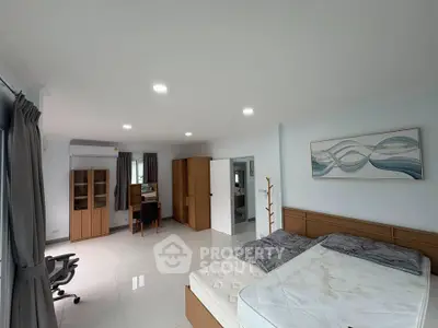 Spacious bedroom with modern furniture and natural light, perfect for relaxation and comfort.