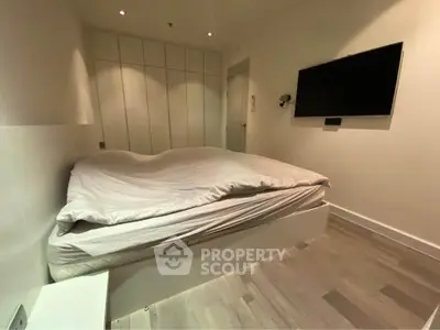 Modern bedroom with sleek design, featuring a wall-mounted TV and ample closet space.