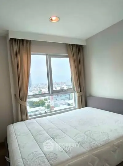Bright bedroom with large window offering stunning city view, featuring elegant curtains and cozy ambiance.
