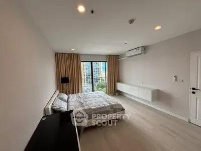 Spacious modern bedroom with large window and city view, featuring minimalist decor and ample natural light.