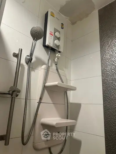 Modern bathroom with sleek shower unit and water heater, featuring contemporary tile design.