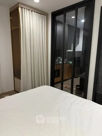 Modern bedroom with sliding glass doors leading to a sleek kitchen area.