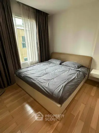 Cozy bedroom with wooden flooring and natural light from large window